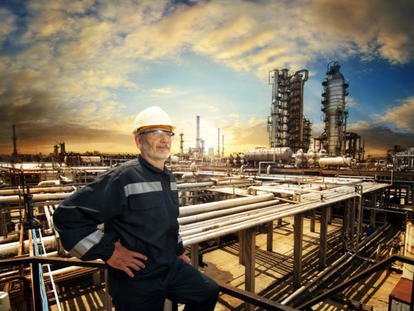 experienced engineer overlooking oil refinery plant in a sunset, dramatic sky colours